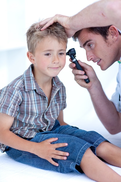 Doktor, der die Ohren eines Patienten mit einem Otoscope überprüft