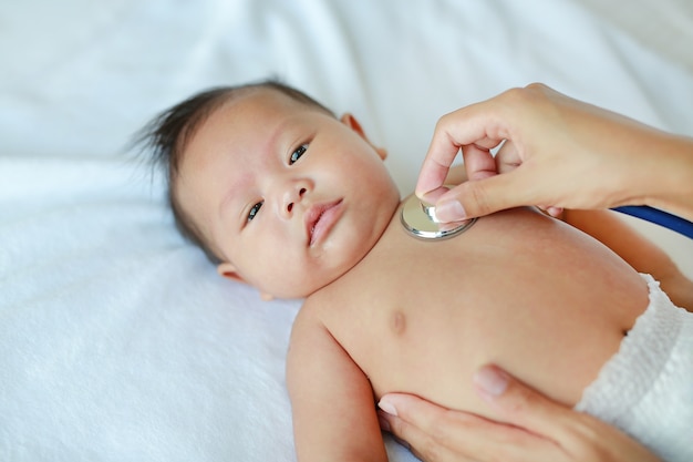 Doktor, der ein Stethoskop verwendet, um auf den Kasten des Babys zu hören Herzschlag zu überprüfen.