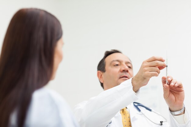 Doktor, der eine Einspritzung für einen Patienten überprüft