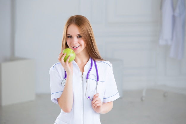 Doktor, der einen grünen Apfel hält. Konzept der gesunden Ernährung.