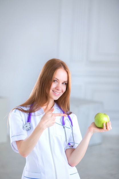 Doktor, der einen grünen Apfel hält. Konzept der gesunden Ernährung.