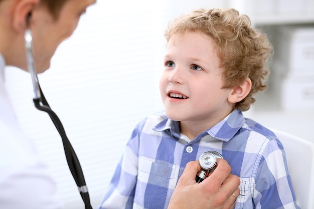 Doktor, der einen Kinderpatienten durch Stethoskop überprüft