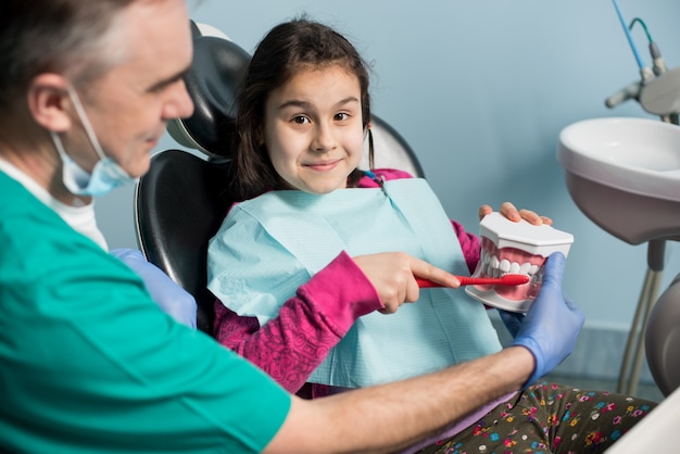Doktor, der geduldige Mädchenzähne in der Zahnarztpraxis behandelt