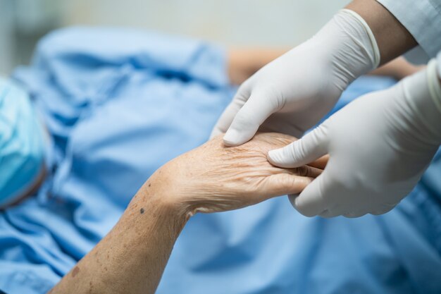 Doktor, der Hand der asiatischen Patientin hält