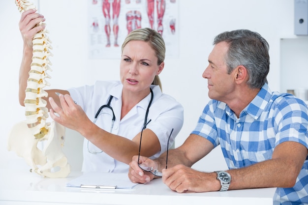 Foto doktor, der ihrem patienten ein dornmodell zeigt