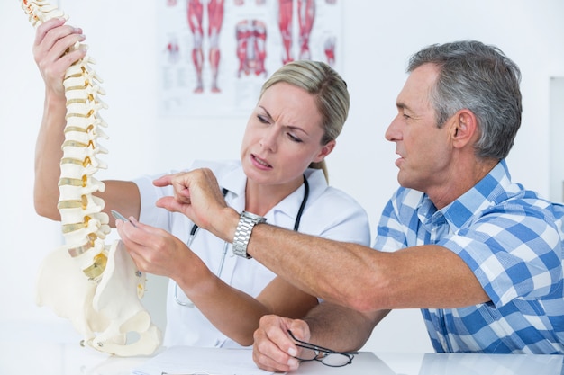 Foto doktor, der ihrem patienten ein dornmodell zeigt