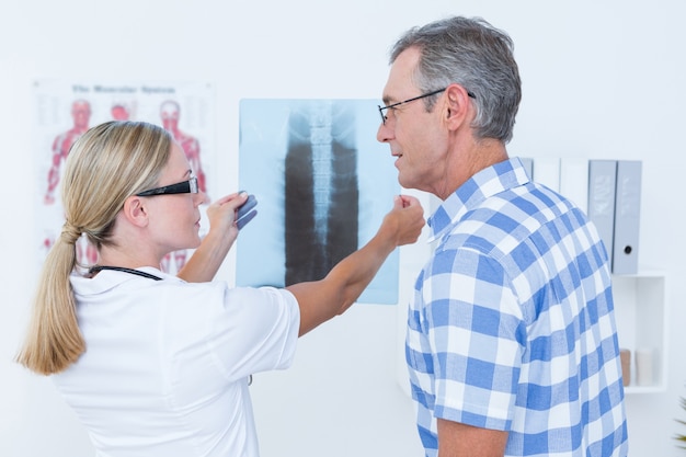 Doktor, der ihrem Patienten Röntgenstrahlen zeigt