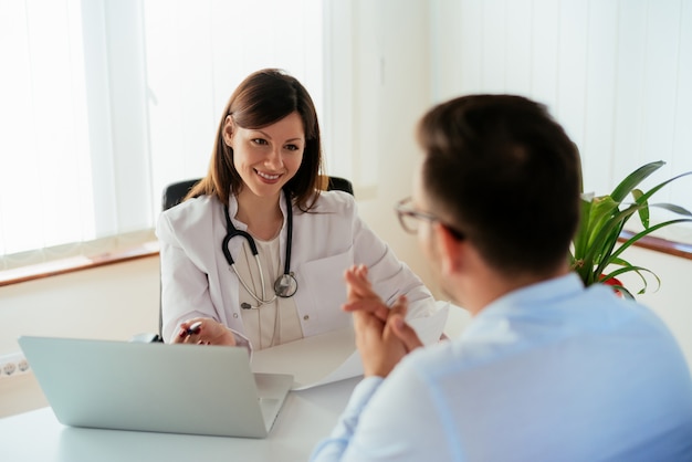 Doktor, der mit Patienten im Büro spricht