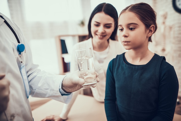 Doktor gibt der Tochter Knallpille und Wasser.