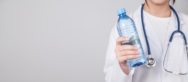 Doktor hält eine Flasche Wasser.