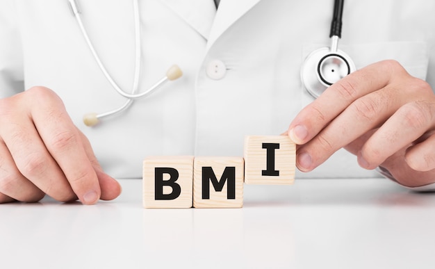 Doktor hält Holzwürfel in seinen Händen mit Text BMI