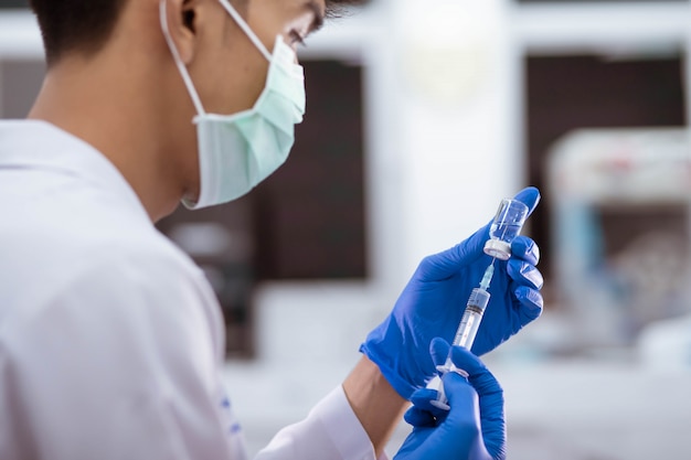 Doktor in der blauen Handschuhfüllspritze mit Impfstoff