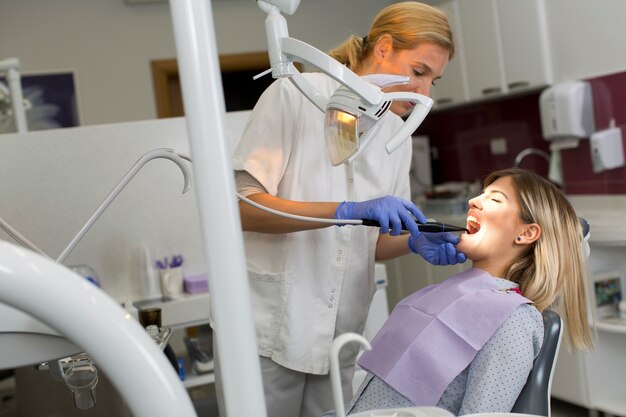Doktor in der Uniform, welche die Zähne des weiblichen Patienten in der zahnmedizinischen Klinik überprüft