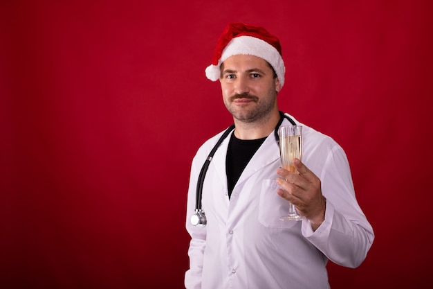 Doktor in der Weihnachtsmütze, die ein Champagnerglas hält