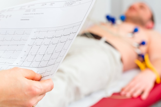 Doktor kontrolliert patient ekg in arztpraxis