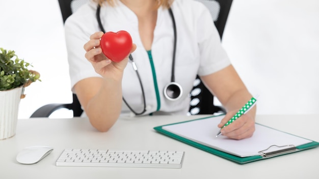 Doktor, Krankenschwester an ihrem Schreibtisch, der ein Herz zeigt.