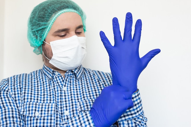 Doktor mit einer Maske, die Handschuhe anzieht.