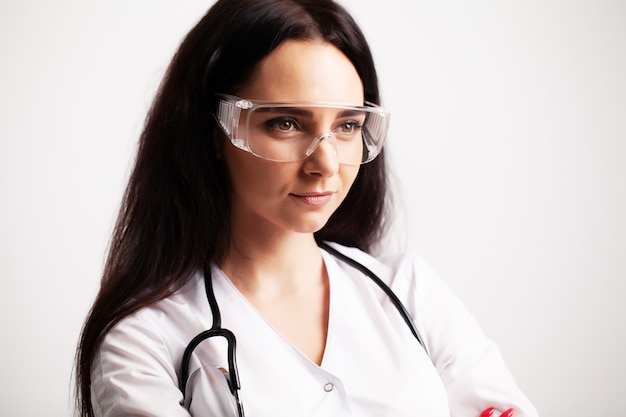 Doktor mit Schutzbrille und Stethoskop auf ihrem Arbeitsbereich