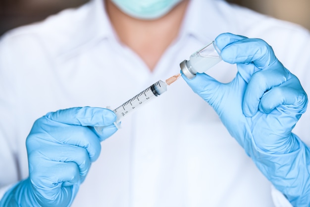 Doktor- oder Krankenschwesterhand, die Grippe, Masern oder HPV-Impfstoffflasche und -spritze mit Nadel hält