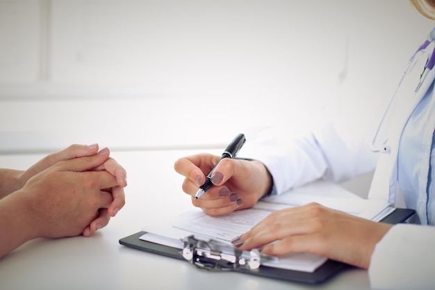 Doktor und Patient diskutieren etwas, nur Hände am Tisch.