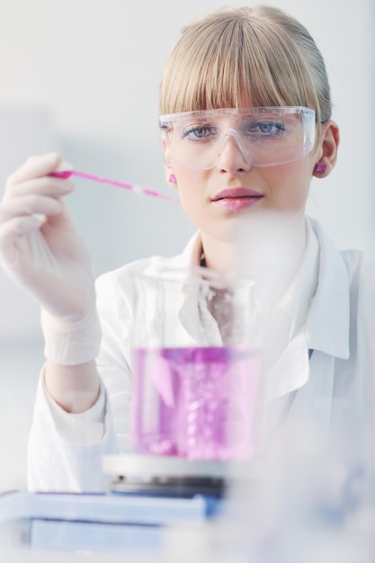 Doktorandin Forscherin hält ein Reagenzglas im hellen Labor der Chemie hoch