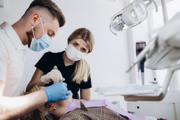 Doktorzahnarzt behandelt Zähne eines schönen jungen Mädchenpatienten Das Mädchen an der Rezeption beim Zahnarzt Doktorzahnarzt behandelt Zahn