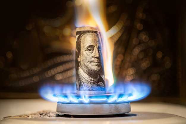 El dólar estadounidense arde en el fuego. Quemador de gas en el fondo de cien dólares. El concepto de la subida del precio del gas en Estados Unidos. Suministro de gas caro