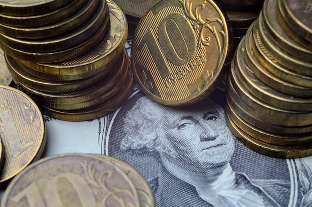 El dólar estadounidense encima del cual se encuentran monedas rusas con un valor nominal de 10 rublos Traducción de las inscripciones en las monedas quot10 rublosquot primer plano