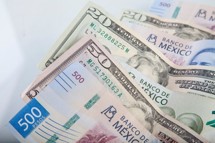 Foto dólar estadounidense y pesos mexicanos sobre fondo blanco.
