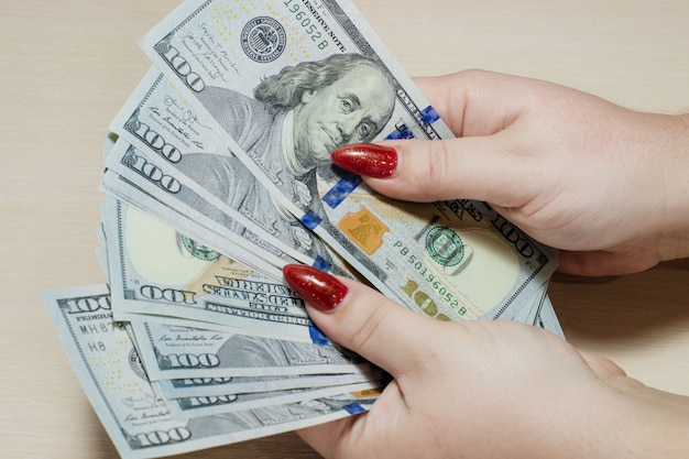 Dólares americanos nas mãos das mulheres. Um homem contando dinheiro, um conceito da economia global.