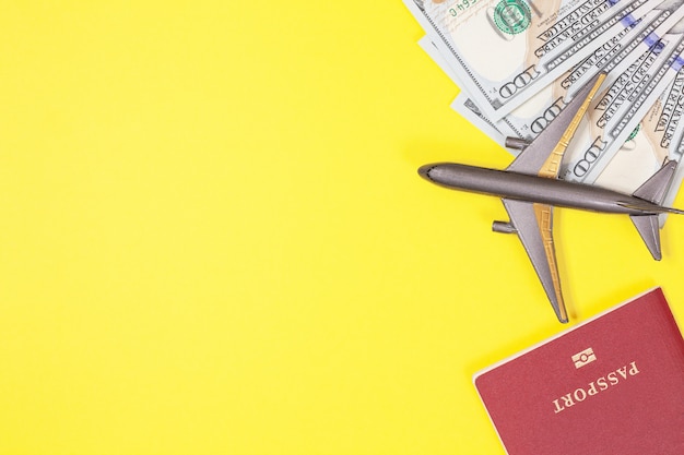 Dólares, avión, auriculares, pasaporte extranjero sobre fondo amarillo. Copia espacio