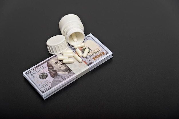 Dólares e pílulas brancas em um fundo preto de perto