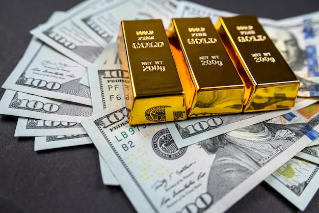 Dollar-Banknoten-Fremdwährungs- und Goldbarrenpreise isoliert auf dunklem Hintergrund