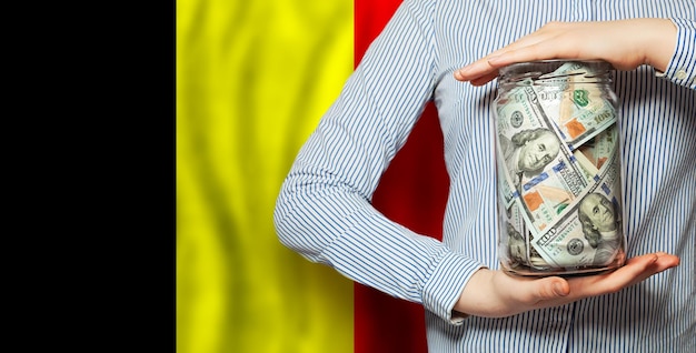 Dollar Geld in der Hand auf belgischer Flagge Hintergrund Politik Wirtschaft und soziale Probleme Konzept