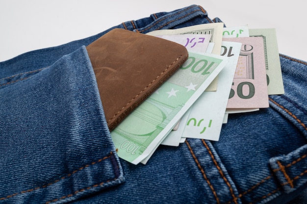 Dollar und Euro ragen aus der Jeanstasche