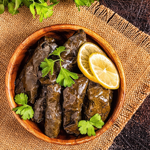 Dolma, folhas de uva recheadas com arroz e carne em fundo escuro, vista superior.