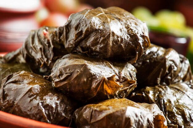 Dolma grego tradicional com carne em folhas de uva molho de iogurte uvas e vinho tinto em um prato de barro foco seletivo