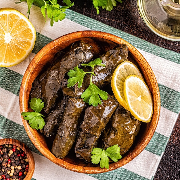 Dolma, hojas de parra rellenas con arroz y carne sobre fondo oscuro, vista superior.