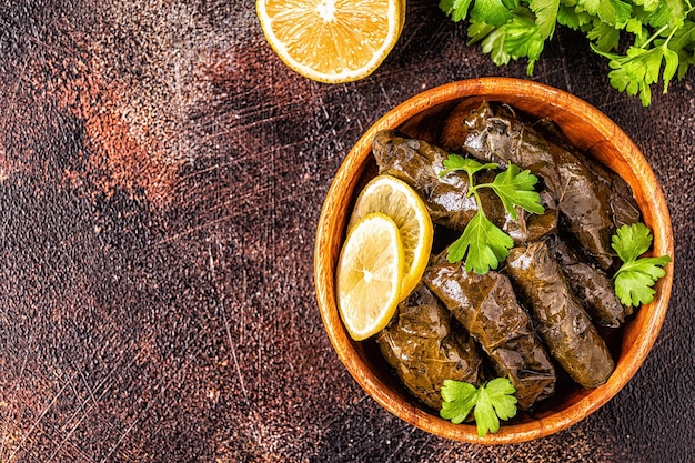 Dolma, hojas de parra rellenas con arroz y carne sobre fondo oscuro, vista superior.