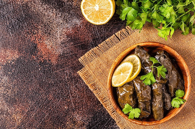 Dolma, hojas de parra rellenas con arroz y carne sobre fondo oscuro, vista superior.