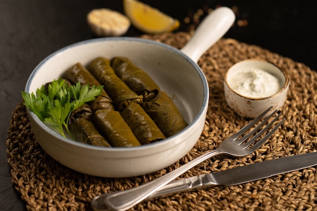 Dolma mit Fleisch, Petersilie und Sauerrahm und Dillsauce. Ein heißes Gericht aus Weinblättern und Hackfleisch mit Sauerrahmsauce.