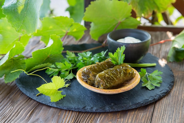 Foto dolma un plato de hojas de uva rellenas con salsa de yogur en una mesa de madera plato oriental tradicional