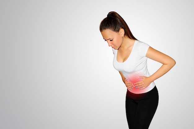 Dolor abdominal. Una mujer joven sufre de dolor en el abdomen. Lugar de dolor marcado con una mancha roja