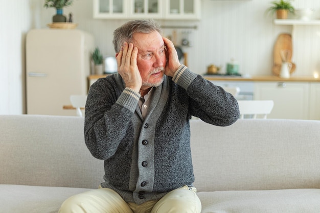 Foto dolor de cabeza dolor infeliz hombre de mediana edad anciano que sufre de dolor de cabeza enfermo frotando las sienes en casa