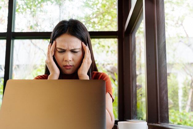 Dolor de cabeza de mujer después de mucho tiempo trabajando en la computadora portátil. concepto de síndrome de oficina