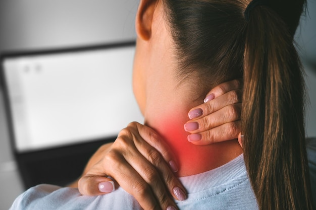 Dolor de cuello después de trabajar en la computadora Mujer joven masajeando el cuello para aliviar el dolor después de trabajar en la computadora