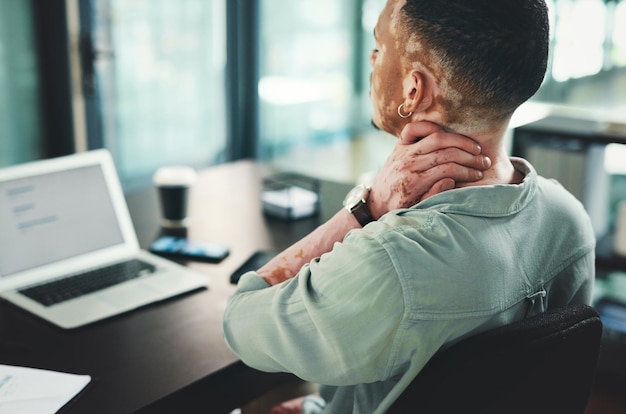 El dolor de cuello es lo peor Toma de un joven hombre de negocios con dolor de cuello mientras usa una computadora portátil en una oficina en el trabajo