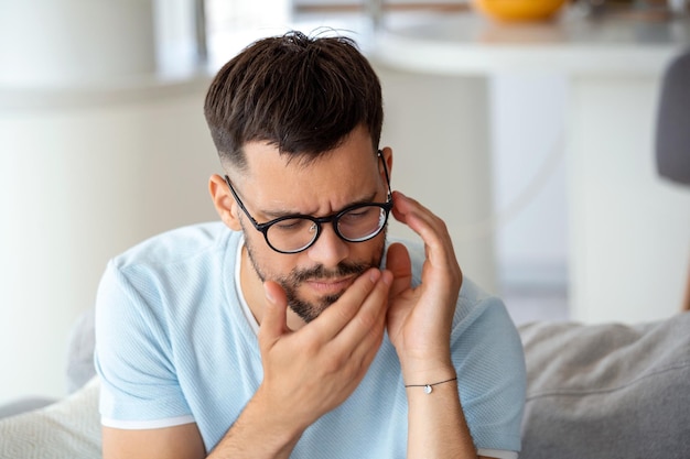 Dolor de dientes y odontología Joven que sufre de terrible dolor de dientes fuertes Tocar la mejilla con la mano Sensación de dolor de muelas Dolor de muelas Cuidado dental y concepto de salud Alta resolución