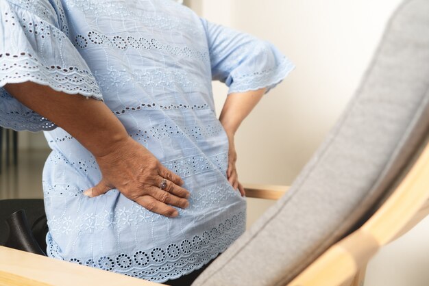 Foto dolor de espalda de anciana en casa, concepto de problema de salud