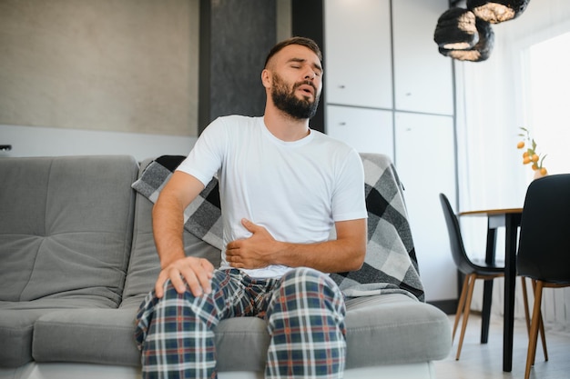 Dolor de estómago hombre con dolor abdominal sufriendo en el hogar problemas de salud concepto
